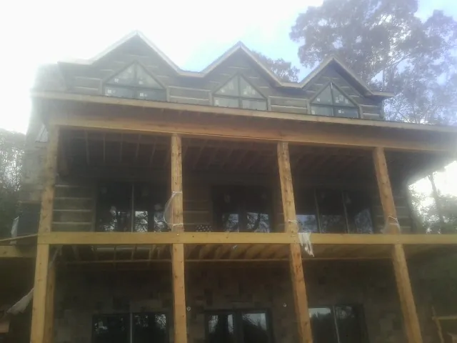 Dormers and porch framing on a large log home under construction — Roof Coating work by our crew in Rosedale