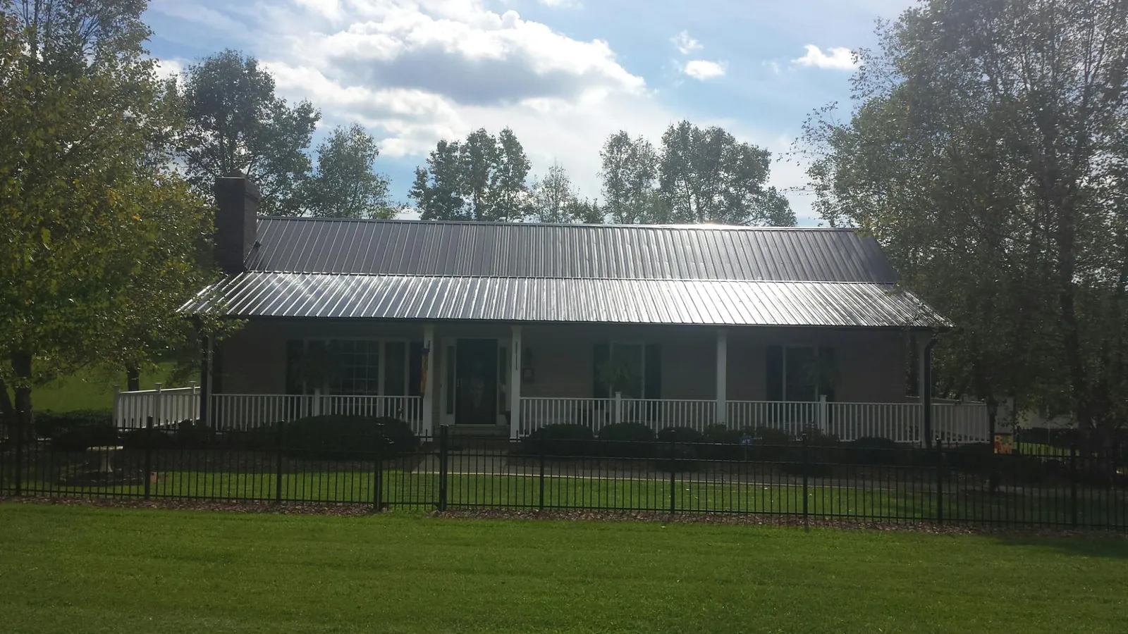 Gray metal roof on a brick ranch with a full width front porch — Gutter Guard Installation work by our crew in Rosedale